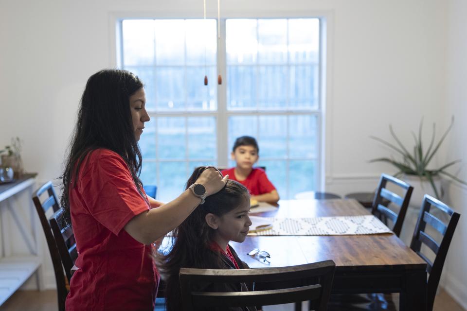 Liz Hurtado adjusts her daughter Leena Lazo's hair before walking to the school bus, Tuesday, Feb. 6, 2024, in Virginia Beach, Va. Hurtado has spent years advocating for electric buses. (AP Photo/Tom Brenner)