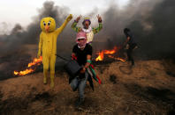 <p>Palestinians wearing costumes are seen at the clashes scene at Israel-Gaza border in the southern Gaza Strip, April 5, 2018. (Photo: Ibraheem Abu Mustafa/Reuters) </p>