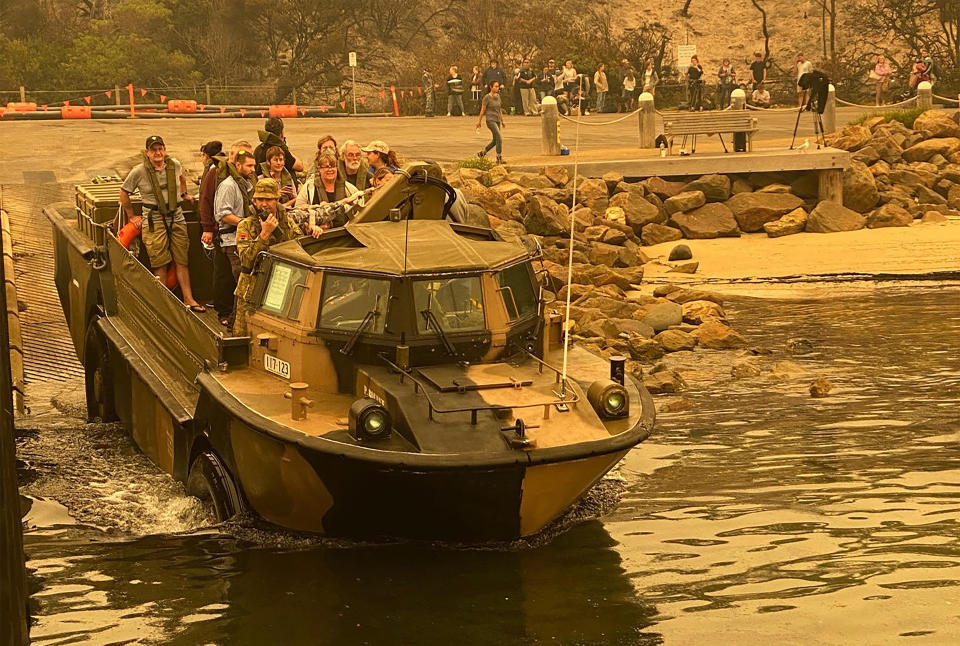In this photo released and taken Jan. 2, 2020, by the Australian Department of Defense, evacuees are transported in a lighter, amphibious, resupply, cargo (LARC) transport amphibious vehicle, from Mallacoota, Victoria, Australia. Navy ships plucked hundreds of people from beaches and tens of thousands were urged to flee before hot weather and strong winds in the forecast worsen Australia's already-devastating wildfires. (Australia Department of Defense via AP)