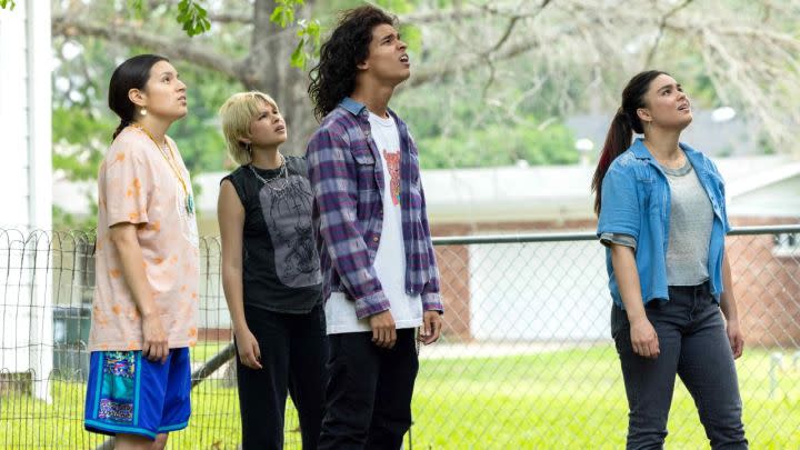 The cast of Reservation Dogs looking up while standing outside,