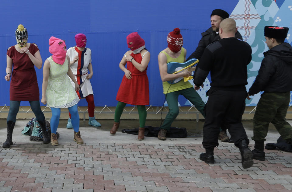 Members of the punk group Pussy Riot, including Nadezhda Tolokonnikova in the blue balaclava and Maria Alekhina in the pink balaclava, are attacked by Cossack militia and a Russian security officer in Sochi, Russia, on Wednesday, Feb. 19, 2014. The group had gathered in a downtown Sochi restaurant, about 30km (21miles) from where the Winter Olympics are being held. They ran out of the restaurant wearing brightly colored clothes and ski masks and were set upon by about a dozen Cossacks, who are used by police authorities in Russia to patrol the streets. (AP Photo/Morry Gash)