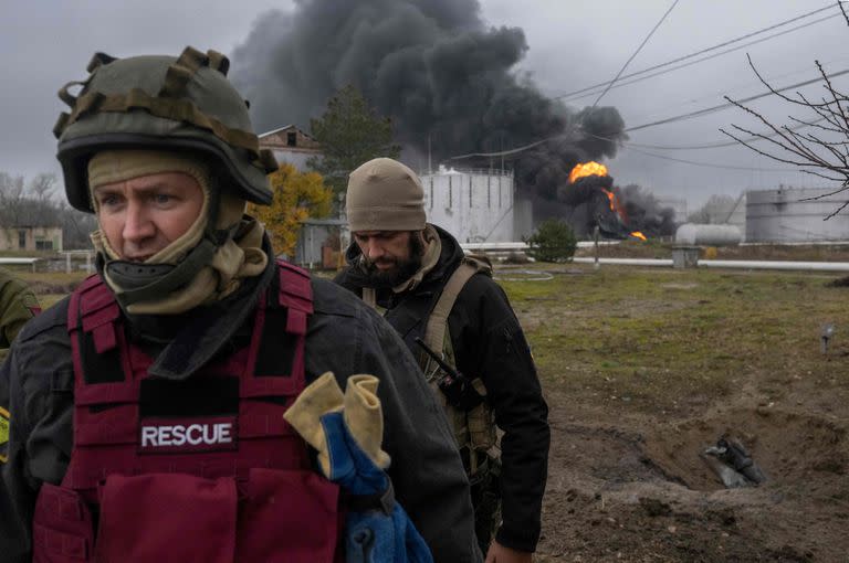 Un miembro del servicio de rescate ucraniano y un soldado inspeccionan la zona mientras sale humo negro de una reserva de petróleo en Kherson el 20 de noviembre de 2022, en medio de la invasión rusa de Ucrania.