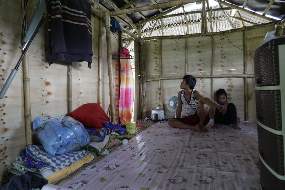 Ronnel Manjares, left, and Trisha May Noche, right, stay inside their house as the rain pours in Tanauan, Batangas province, Philippines, Wednesday, July 15, 2020. Their 16-day-old son Kobe Manjares was heralded as the country's youngest COVID-19 survivor. But the relief and joy proved didn't last. Three days later, Kobe died on June 4 from complications of Hirschsprung disease, a rare birth defect. (AP Photo/Aaron Favila)