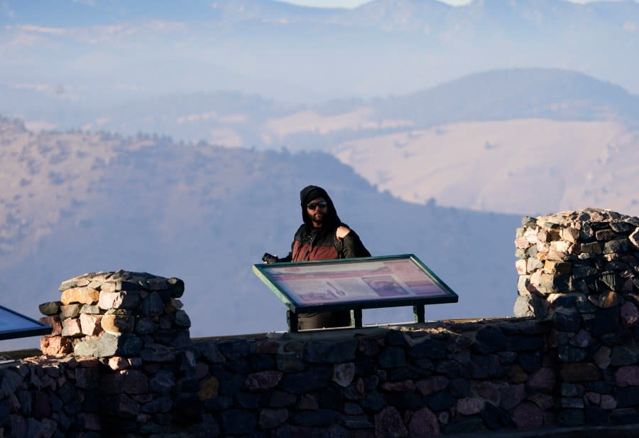 A visitor takes in the vista of the Rocky Mountains while at Buffalo Bill Cody’s gravesite on Lookout Mountain, late Wednesday, Feb. 10, 2021, in Golden, Colo. (AP Photo/David Zalubowski)