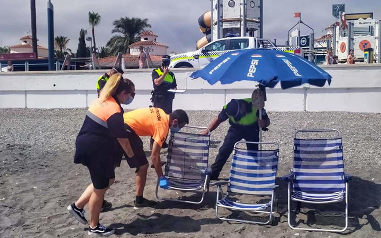 Police and beach patrol officers remove folding chairs and tables from a beach on the Costa del Sol - ASA/GC/SM 