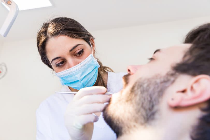 A female dentist gives a male patient a basic examination