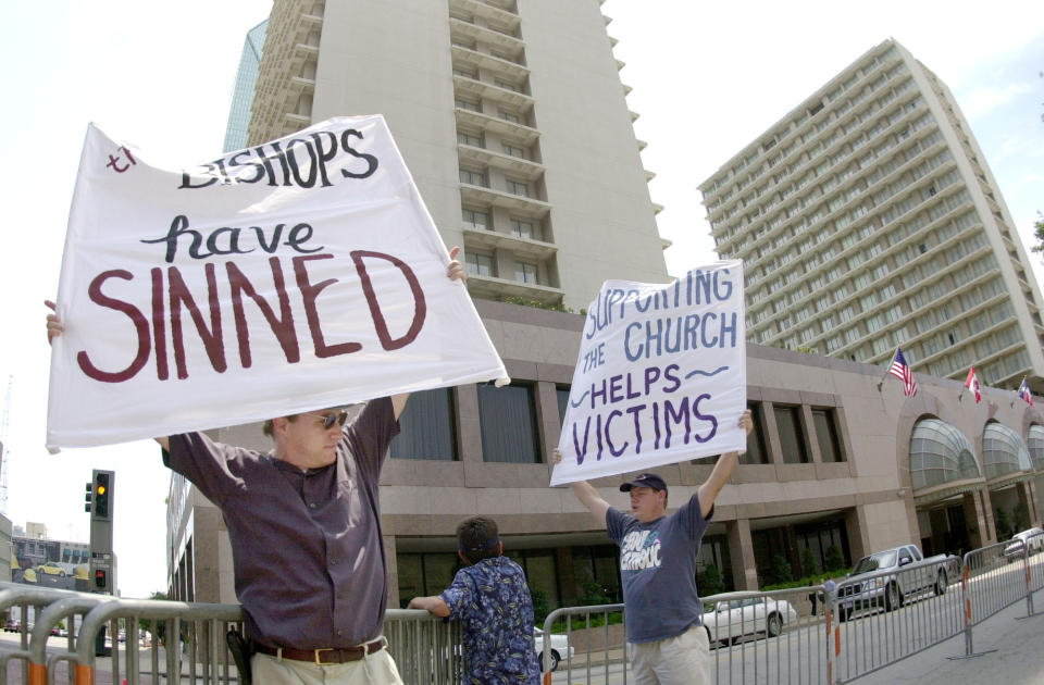 FILE - Dave West, left, and his brother Larry West, both of Fort Worth, Texas, demonstrate outside the hotel where the U.S. Conference of Catholic Bishops are meeting in Dallas on Friday, June 14. 2002. The nation's Catholic bishops begin their fall annual meeting Monday, Nov. 14, 2022, on the 20th anniversary of their adoption of policies designed to root out sexual abuse and abusers in the priesthood — policies adopted amid the scandals of 2002 when the Boston Globe's Spotlight investigative team exposed widespread patterns of abuse and coverup. (AP Photo/Charlie Riedel, File)