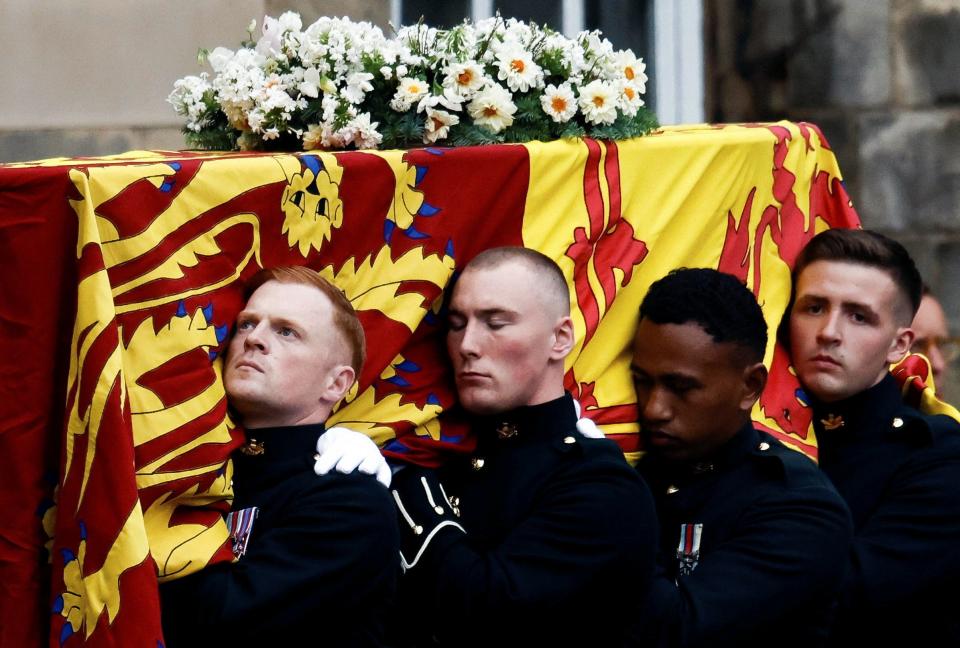 Pallbearers carry the coffin of Queen Elizabeth II, draped with the Royal Standard of Scotland, as it arrives at Holyroodhouse, where it will lie in rest for a day in Edinburgh.