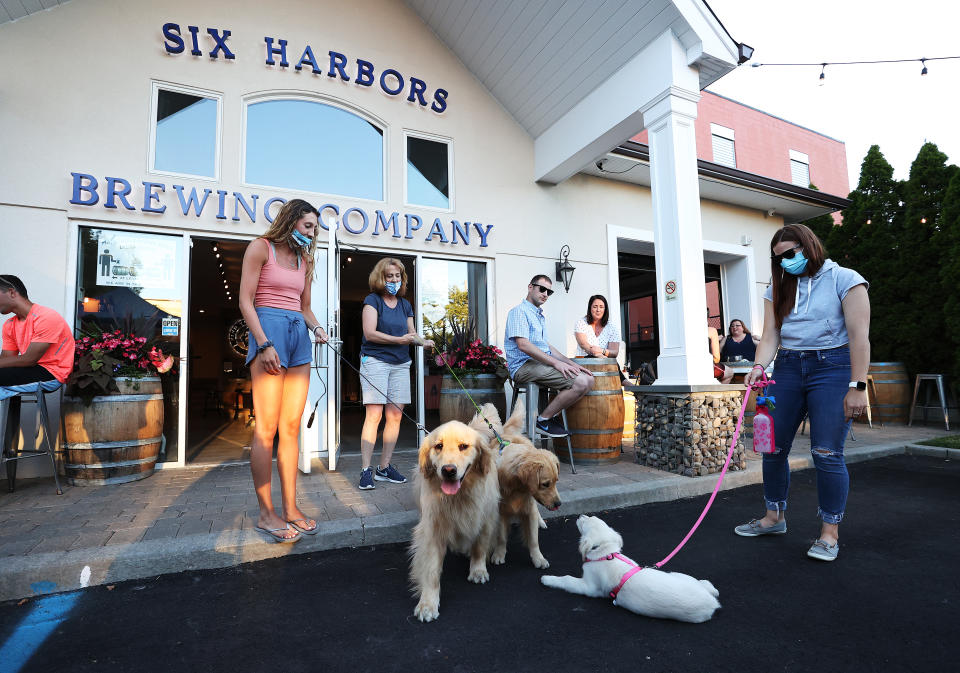 Owner Karen Heuwetter (L) introduces her golden retrievers Buddy and Barley to customers at the Six Harbors Brewing Company on June 24, 2020 in Huntington, New York. (Photo by Al Bello/Getty Images)