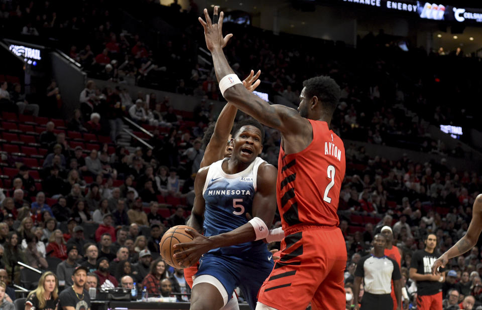 Minnesota Timberwolves guard Anthony Edwards, left, drives to the basket against Portland Trail Blazers center Deandre Ayton, right, during the first half of an NBA basketball game in Portland, Ore., Tuesday Feb. 13, 2024. (AP Photo/Steve Dykes)
