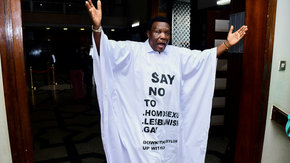 Ugandan MP John Musira dressed in an anti-gay gown gesturing as he leaves the chambers during the debate of the Anti-Homosexuality bill