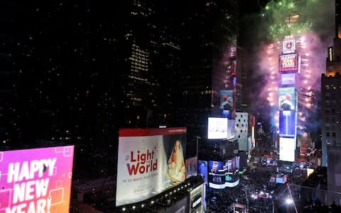 Fireworks erupt from Times Square's iconic advertising displays - Credit: AP