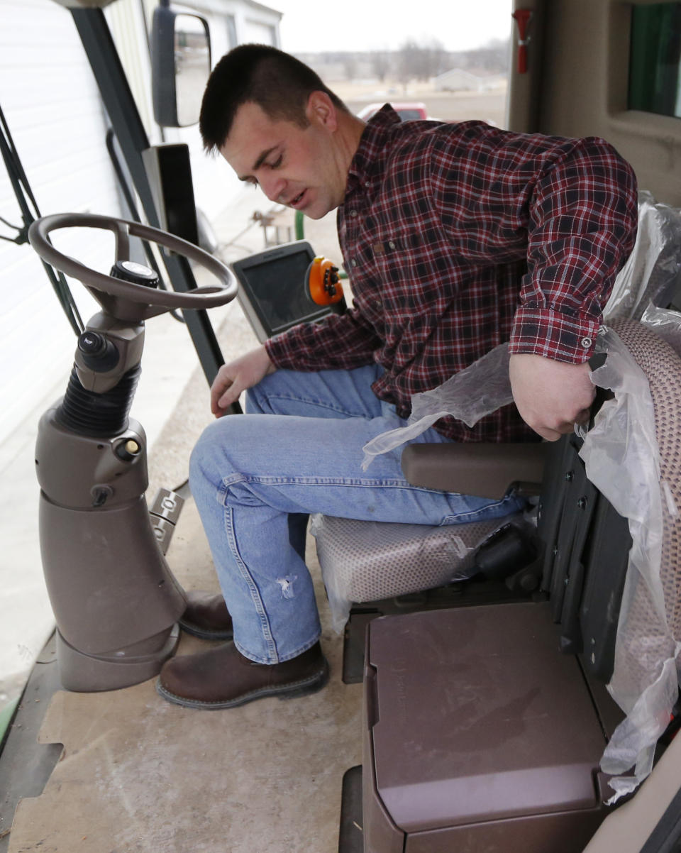 Nick Guetterman folds a seat as he climbs into a combine on his farm near Bucyrus, Kan., Wednesday, Feb. 19, 2014. Farmers from across the nation gathered in Washington this month for their annual trek to seek action on the most important matters in American agriculture. But this time, a new issue emerged: growing unease about how the largest seed companies are gathering vast amount of data from sensors on tractors, combines and other farm equipment. The sensors measure soil conditions, seeding rates, crop yields and many other variables. (AP Photo/Orlin Wagner)