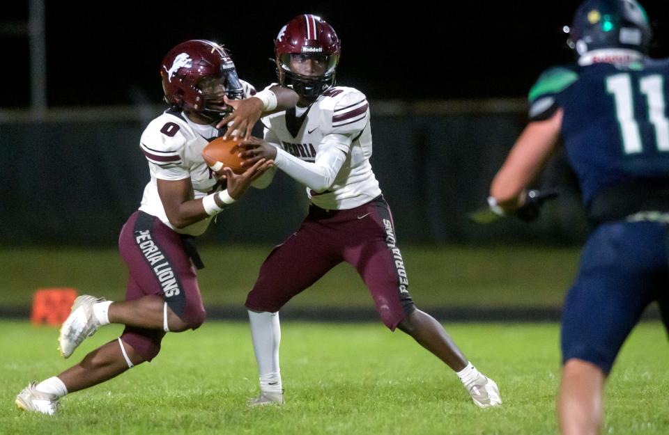 Peoria High quarterback Breon Green hands the ball off running back Detaurion Pollard in the second half of their Week 2 football game Friday, Sept. 6, 2024 at Richwoods Stadium. The Lions defeated the Irish 46-40.