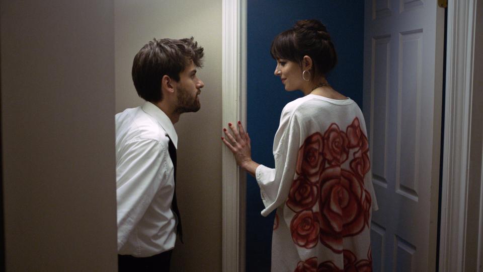 A man looks at a woman standing in a doorway