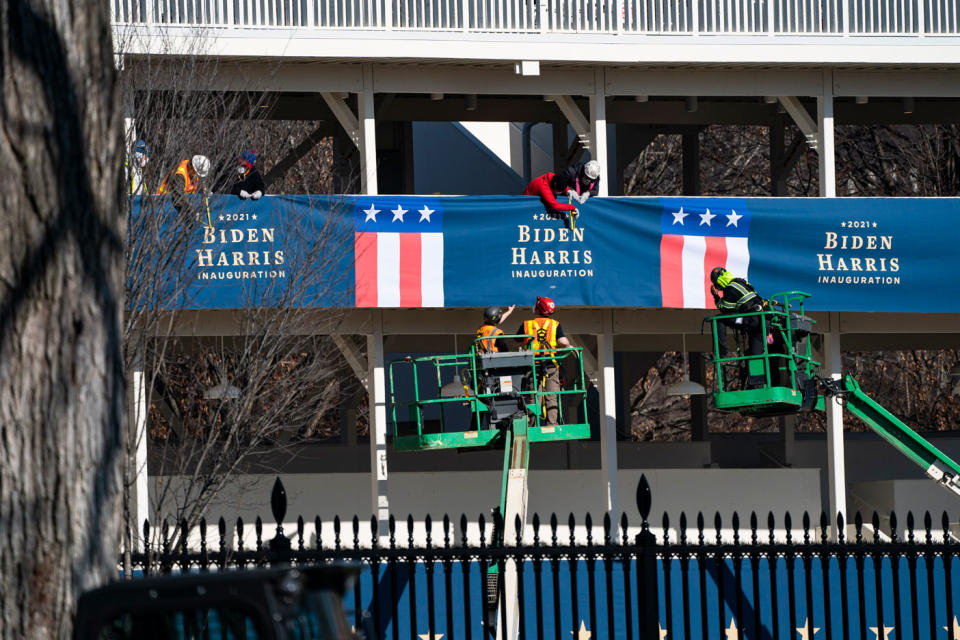 Workers hang banners featuring the names of Joe Biden and Kamala Harris before inauguration day.