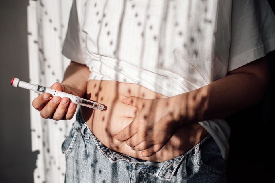 Injections for weight loss with Semaglutide. An obese woman gives a hormone glucagon-like peptide-1 (GLP-1) injection into the abdomen with a pen syringe.