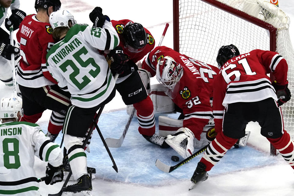 Chicago Blackhawks goaltender Kevin Lankinen (32) makes a save on a shot as Dallas Stars left wing Joel Kiviranta (25) battles for the puck against Chicago Blackhawks defenseman Connor Murphy (5) and right wing MacKenzie Entwistle (58) during the first period of an NHL hockey game in Chicago, Sunday, May 9, 2021. (AP Photo/Nam Y. Huh)