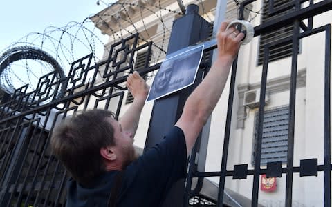 An activists hangs portraits of journalist Arkadi Babchenko to the fence of Russian embassy in Kiev, on May 30, 2018,  - Credit: SERGEI SUPINSKY/AFP