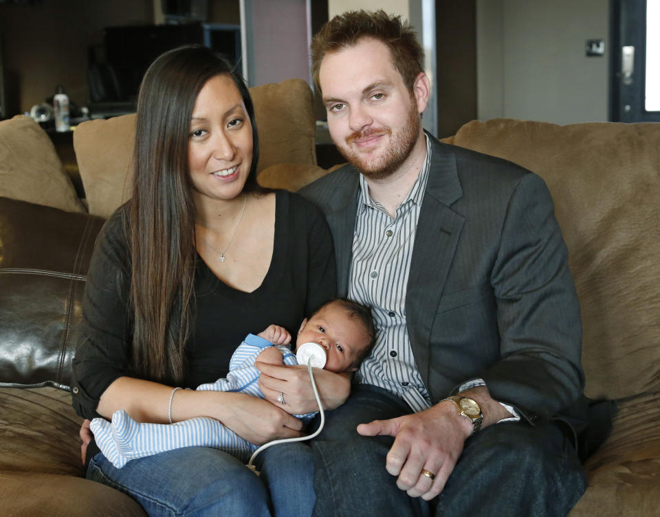 Jennifer Rogers, left, and her husband Nyle Rogers, right, smile as they hold their baby Jack Nicolas Rogers, in their home in Edmond, Okla., Tuesday, Jan. 14, 2014. Jack Nicolas Rogers was born Dec. 21, 2013. Rogers is formerly Jennifer Doan, a Plaza Towers schoolteacher who was the subject of what became an iconic photograph of the Moore, Okla. tornado as firefighters are shown freeing a debris-covered Doan from the rubble of a collapsed wall. Doan was pregnant with Jack Nicolas at the time. Jack's middle name, Nicolas, is in memory of one of her students, who died in the tornado. (AP Photo/Sue Ogrocki)