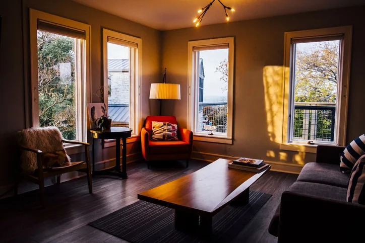 A cozy living room at sunset with furniture and windows offering a view of trees