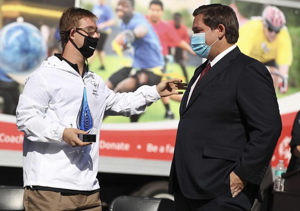FILE - In this Nov. 19, 2020, file photo, athlete Chris Nikic, left, reaches out to Florida Gov. Ron DeSantis during a Special Olympics USA Games event at Special Olympics Florida Headquarters in Clermont, Fla. (Stephen M. Dowell/Orlando Sentinel via AP, File)