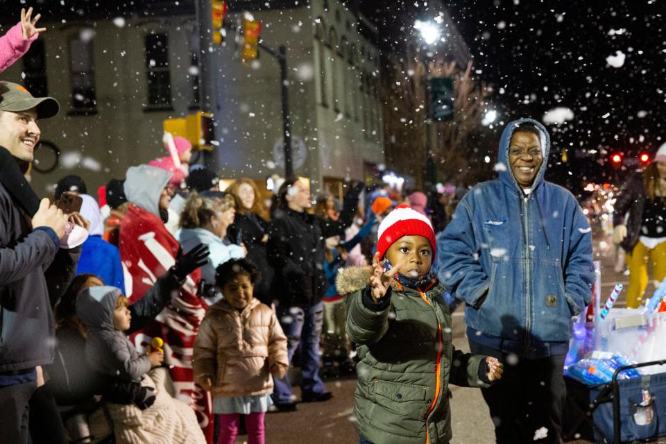 Parade attendees reach out for fake snow drifting down from the Scout Pack 115 float during the Jackson Downtown Christmas Parade on Monday, December 12, 2022, in Jackson, Tenn. 