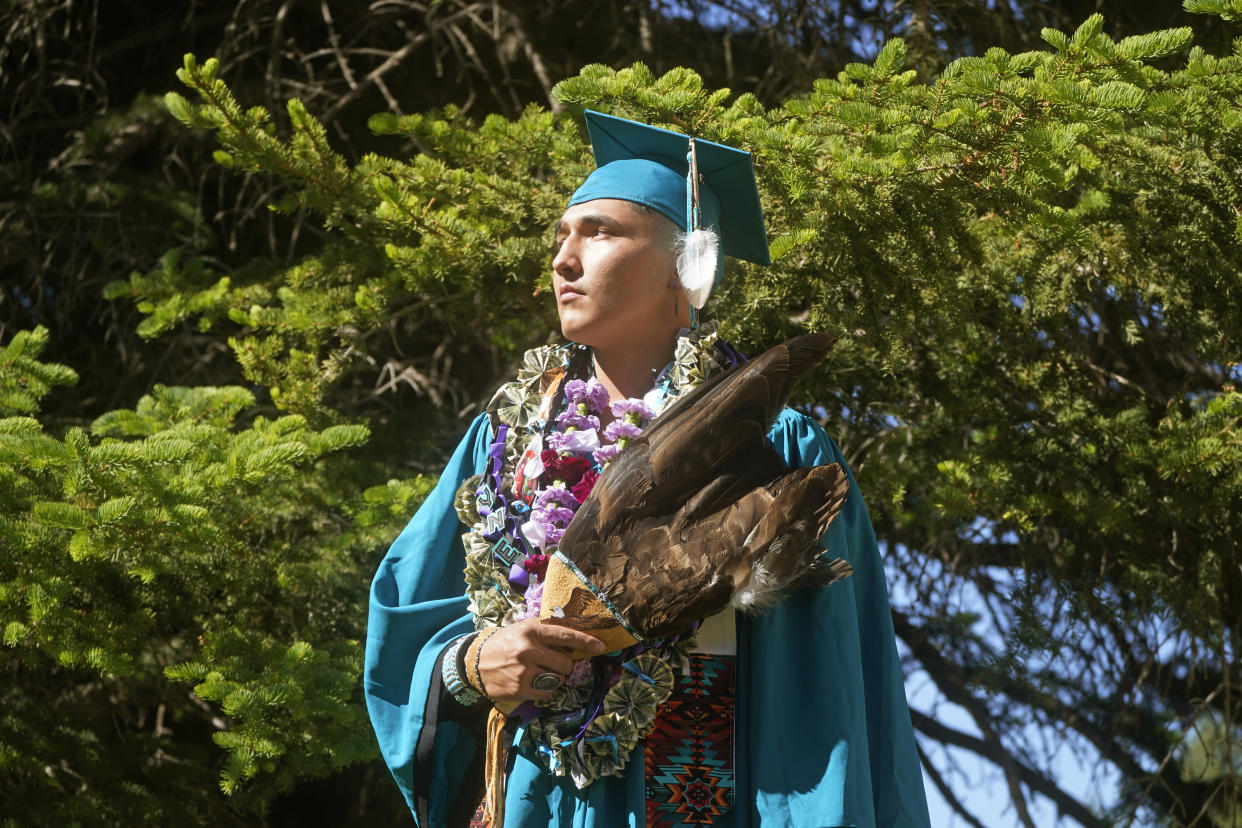 Dayne Hudson, member of the Paiute Indian Tribe of Utah, holds his eagle feather fan before the Canyon View High School graduation Wednesday, May 25, 2022, in Cedar City, Utah. Hudson said it was important to wear eagle feathers and a beaded cap to represent his family and honor those who were stopped from doing so under the old rule. (AP Photo/Rick Bowmer)