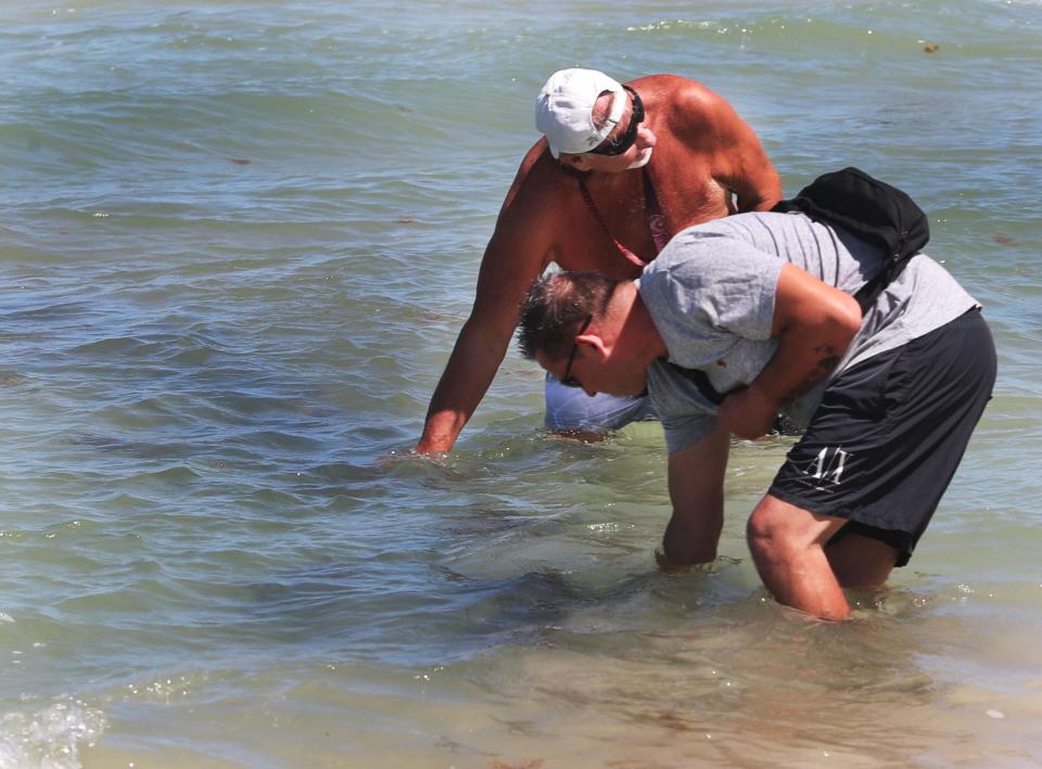 Beachgoers check out a possible shipwreck, Friday, April 21, 2023, in the 3200 block in Daytona Beach Shores.