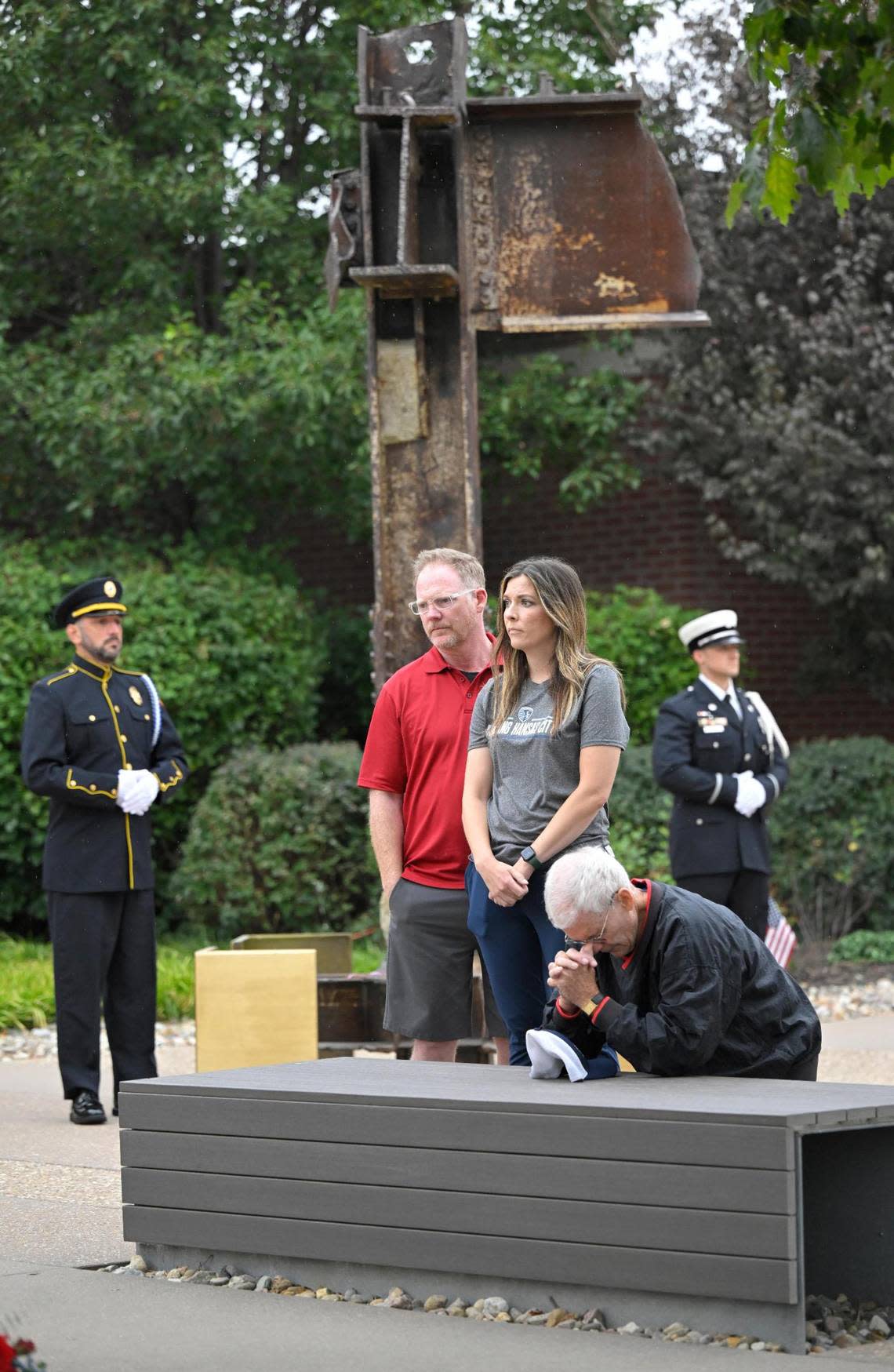 George Flinn, right, of Overland Park, kneeled in prayer as he paid his respects to his former roommate, Capt. Charles ‘Chic’ Burlingame III, pilot of Flight 77, the highjacked plane that was flown into the Pentagon on 9/11/2001. Flinn attended the 22nd anniversary ceremony on Monday, Sept. 11, at 9/11 Memorial in Overland Park where a a 14-foot, 2.5 ton steel beam from ground zero stood. Craig and Ashlee Ruster, also of Overland Park, also paid their respects.