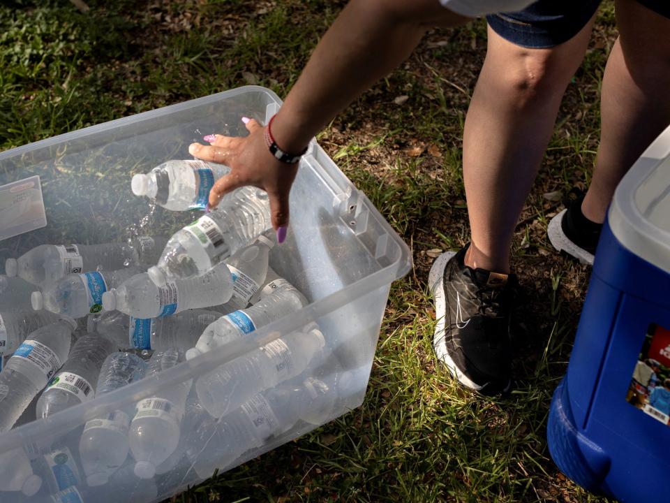 person throws water bottles in a plastic bin