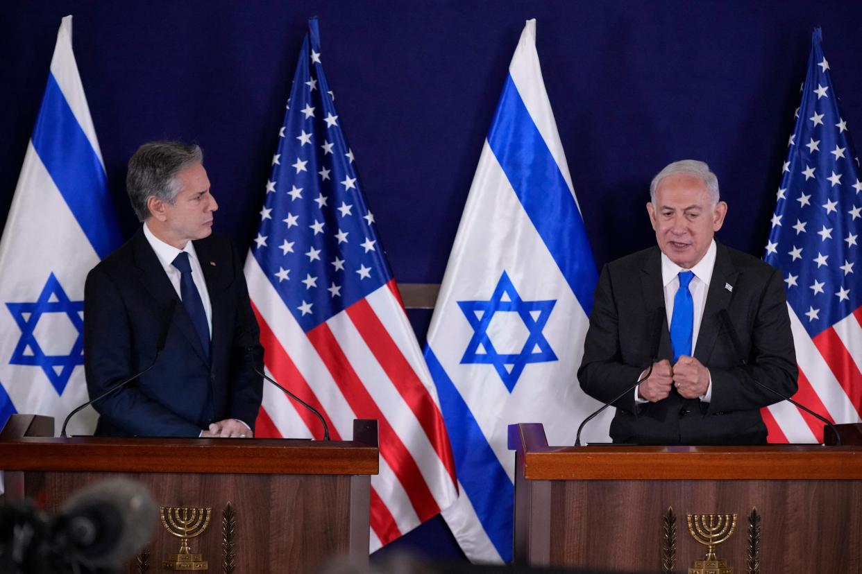 Two men stand behind lecterns and speak, with the American and Israeli flags behind them.