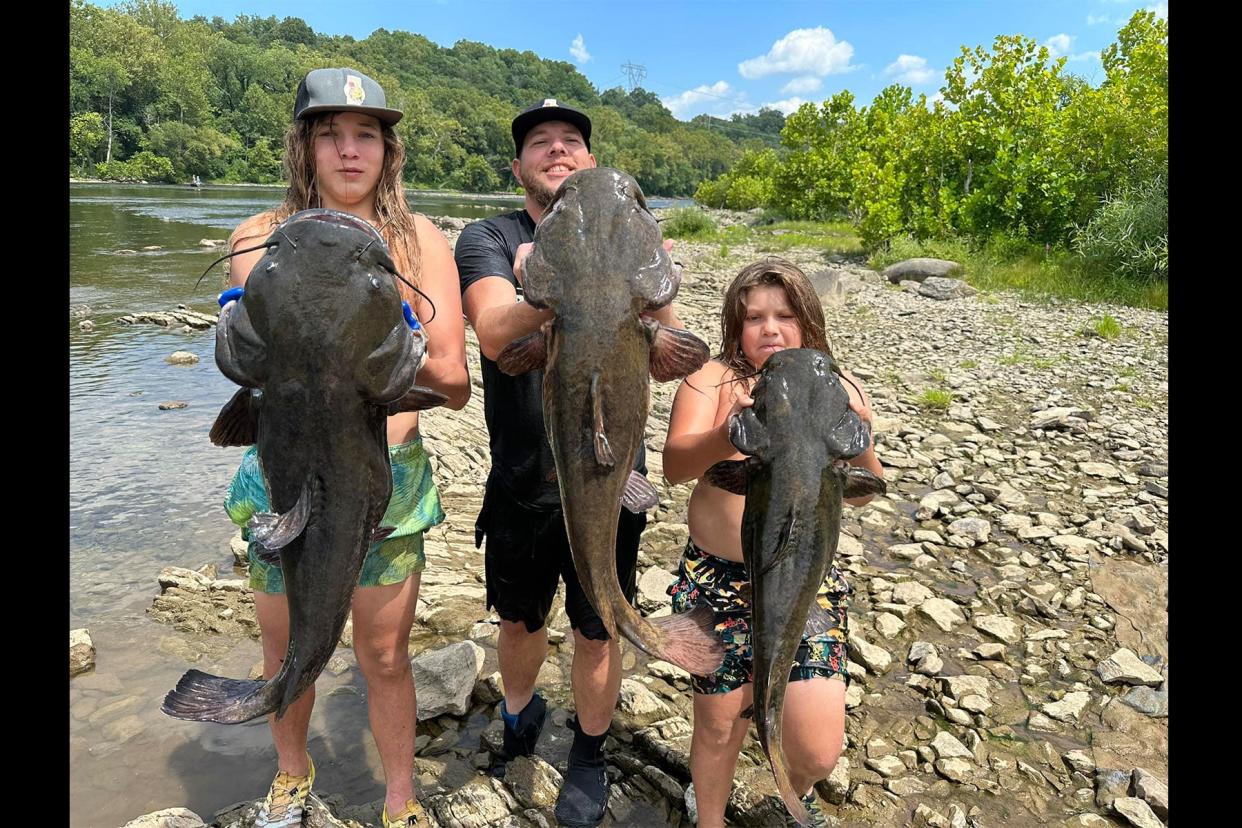 Nathan Wayne Williams and sons pose with three massive flathead catfish.