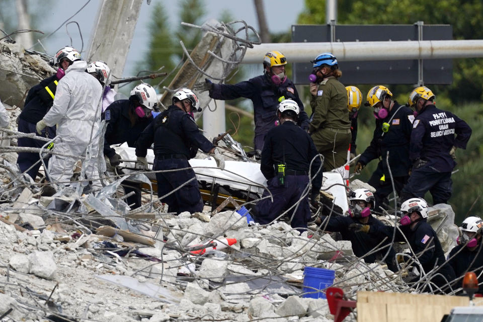 Image: Rescue workers move a stretcher containing recovered remains at the site of the collapsed Champlain Towers South condo building, in Surfside, Fla., on July 5, 2021. (Lynne Sladky / AP)