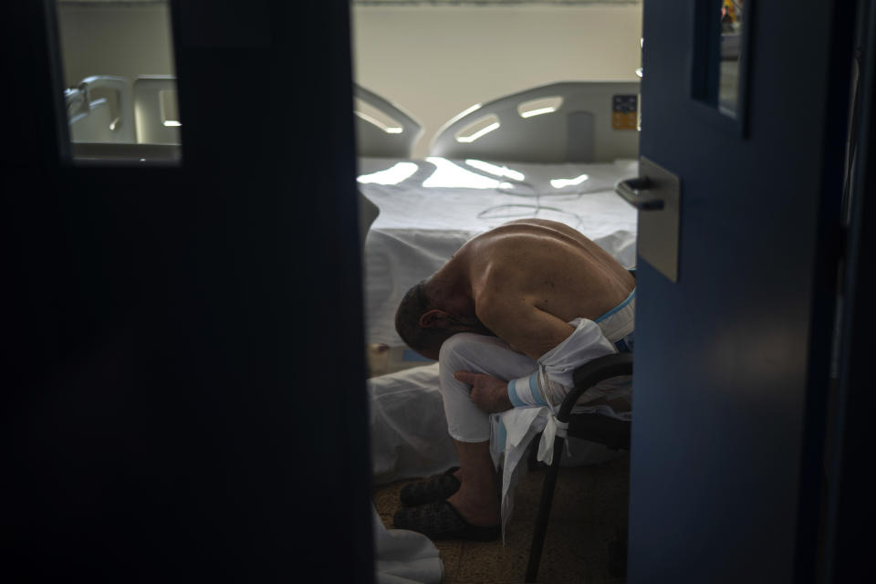 Un paciente de COVID-19 apoya la cabeza sobre las rodillas en un hospital de Barcelona el 18 de noviembre del 2020. (AP Photo/Emilio Morenatti)