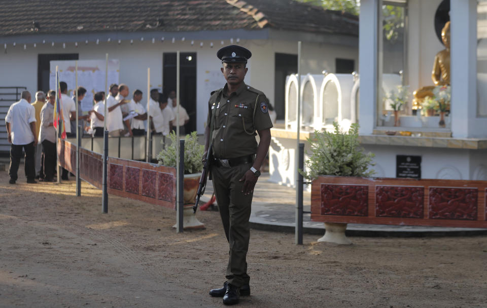 Sri Lankans queue up to cast their votes as a police officer stands guard at a polling station during the presidential election in Colombo, Sri Lanka, Saturday, Nov. 16, 2019. Polls opened in Sri Lanka’s presidential election Saturday after weeks of campaigning that largely focused on national security and religious extremism in the backdrop of the deadly Islamic State-inspired suicide bomb attacks on Easter Sunday. (AP Photo/Eranga Jayawardena)
