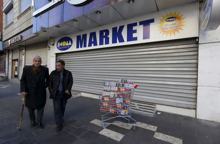 Men walk past a closed supermarket in Sur district which is partially under curfew, in the southeastern city of Diyarbakir, Turkey, December 8, 2015. REUTERS/Murad Sezer