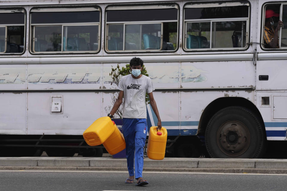 FILE - A Sri Lankan bus worker carries empty containers searching for fuel in Colombo, Sri Lanka on March 2, 2022. Sri Lanka’s already dire economic crisis has deepened as oil prices hover near $110 a barrel. Vehicles are stranded with empty tanks, power cuts are depriving students of study time for exams and shopping mall air conditioners are being switched off to conserve energy. (AP Photo/Eranga Jayawardena, File)