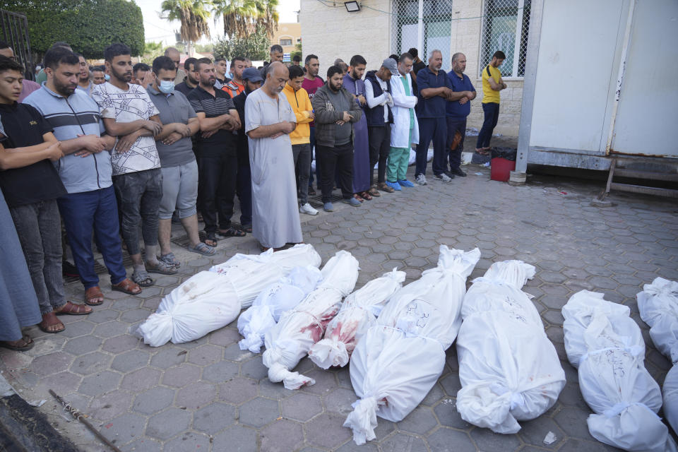 Friends and relatives pray for Palestinians killed in the Israeli bombardment of the Gaza Strip at Al-Aqsa Hospital in Deir Al-Balah, Sunday, Oct. 22, 2023. AP Photo/Hatem Moussa)