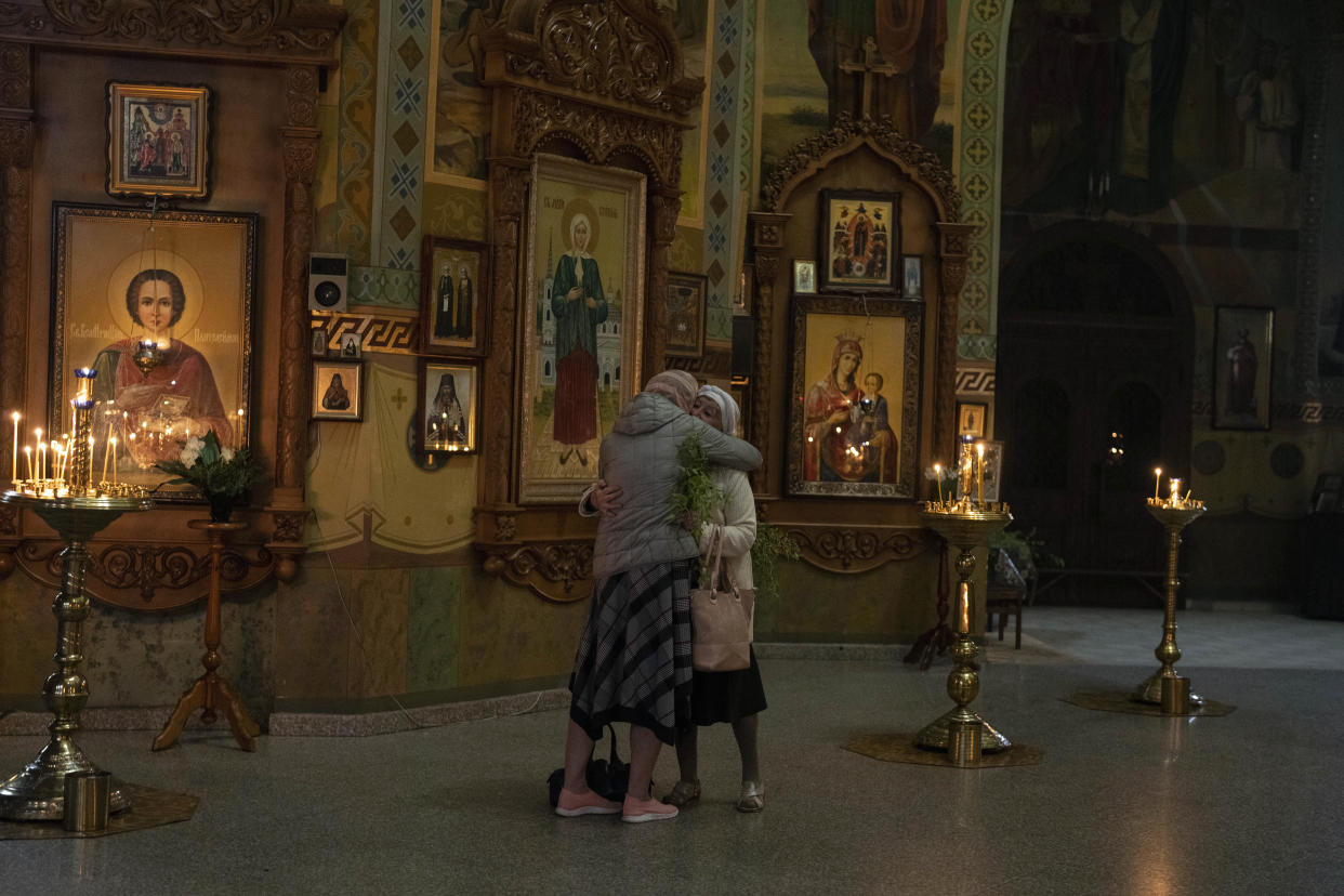 Two women hug each other during an Orthodox Palm Sunday service.