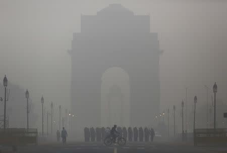 A man rides his bicycle next to Indian soldiers marching in front of India Gate on a smoggy morning in New Delhi, India, December 1, 2015. REUTERS/Anindito Mukherjee