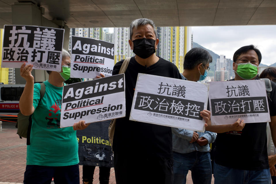 Pro-democracy activist Lee Cheuk-yan, center, holds placards as he arrives at a court in Hong Kong Thursday, April 1,2021. Seven pro-democracy advocates, including media tycoon Jimmy Lai and veteran of the city's democracy movement Martin Lee, are expected to be handed a verdict for organizing and participating in an illegal assembly during massive anti-government protests in 2019 as Hong Kong continues its crackdown on dissent. (AP Photo/Vincent Yu)