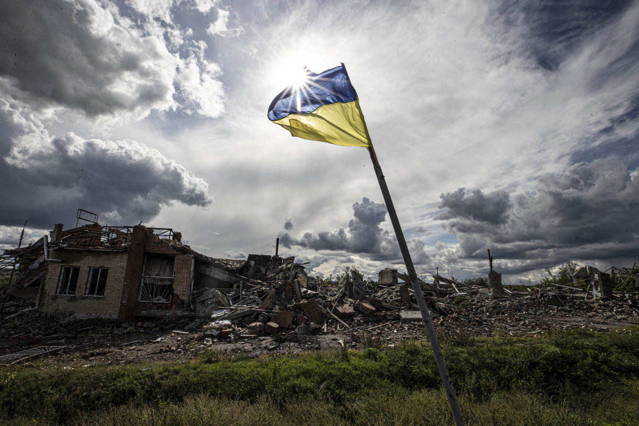 A Ukrainian flag waves in a heavily damaged residential area in the village of Dolyna.