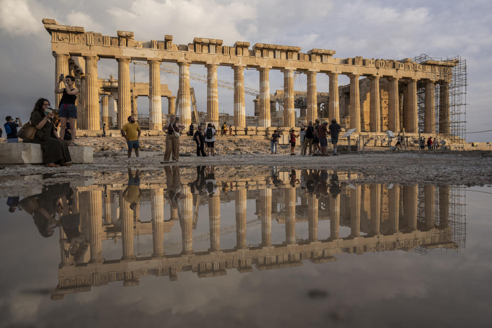 FILE - The 2,500-year-old Parthenon temple is reflected on a puddle following a rainfall as tourists visit the ancient Acropolis hill of Athens, on Tuesday, June 13, 2023. One of the world's most intractable cultural disputes has sprung to the fore again after a Turkish official cast doubt on the existence of proof cited by Britain that it had legally acquired the Parthenon Marbles, 2,500-year-old sculptures taken from the Acropolis in Athens. (AP Photo/Petros Giannakouris, File)