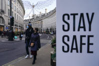 People wear face masks as they walk, in Regent Street, in London, Sunday, Nov. 28, 2021. Britain's Prime Minister Boris Johnson said it was necessary to take "targeted and precautionary measures" after two people tested positive for the new variant in England. He also said mask-wearing in shops and on public transport will be required. (AP Photo/Alberto Pezzali)