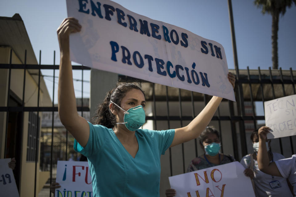 A nurse holds up a sign that reads, 