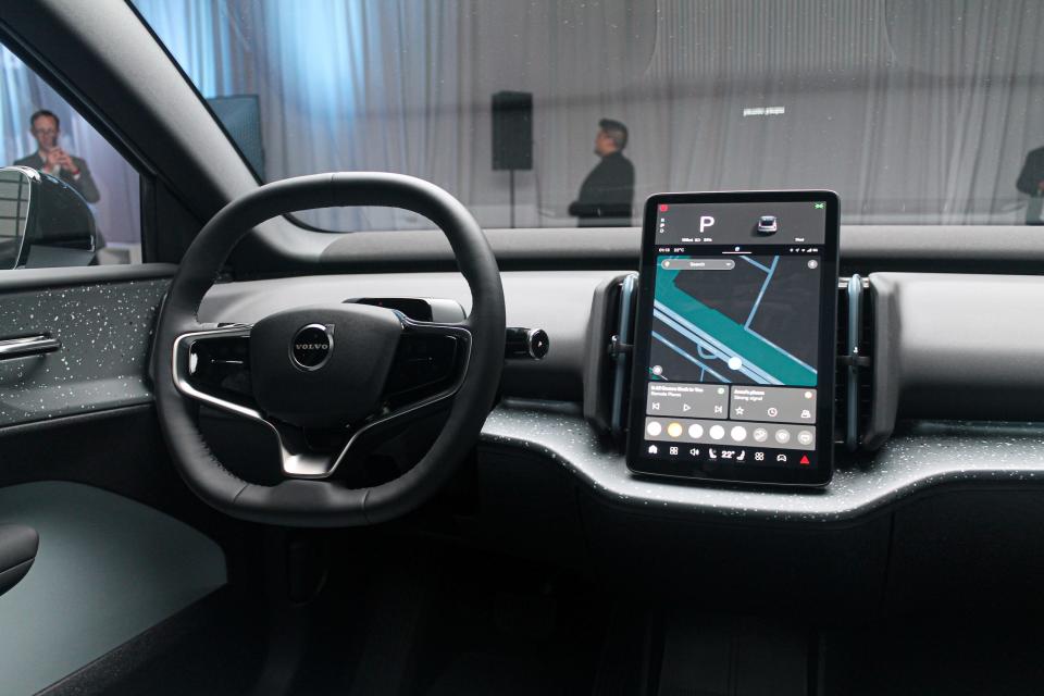 The steering wheel of the Volvo EX30, which has a large touchscreen in the centre of the dashboard that is showing a map.