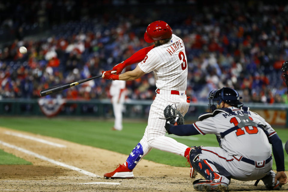 Philadelphia Phillies' Bryce Harper, left, hits a homerun off Atlanta Braves relief pitcher Shane Carle during the seventh inning of a baseball game, Sunday, March 31, 2019, in Philadelphia. At right is catcher Brian McCann. (AP Photo/Matt Slocum)