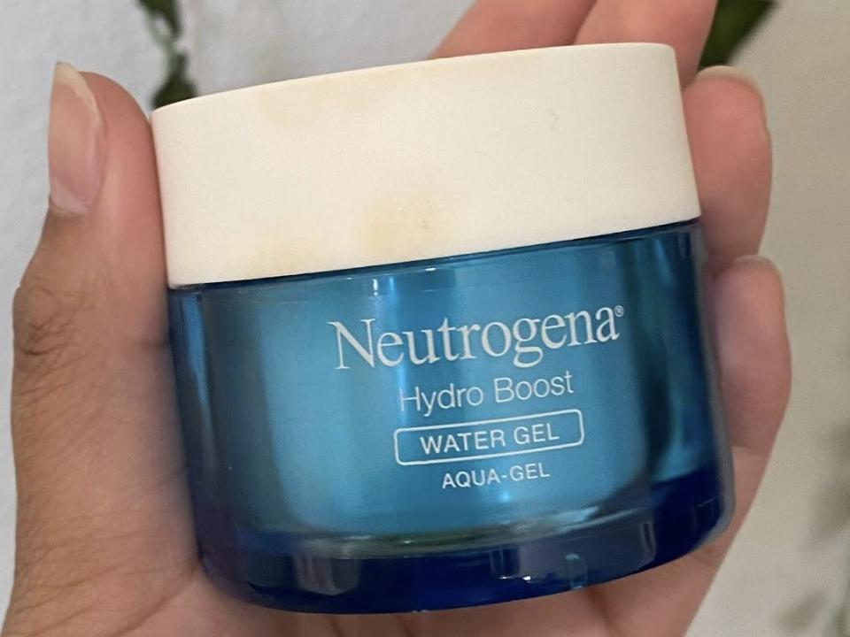 The writer holds a small blue container with white "Neutrogena" text on it