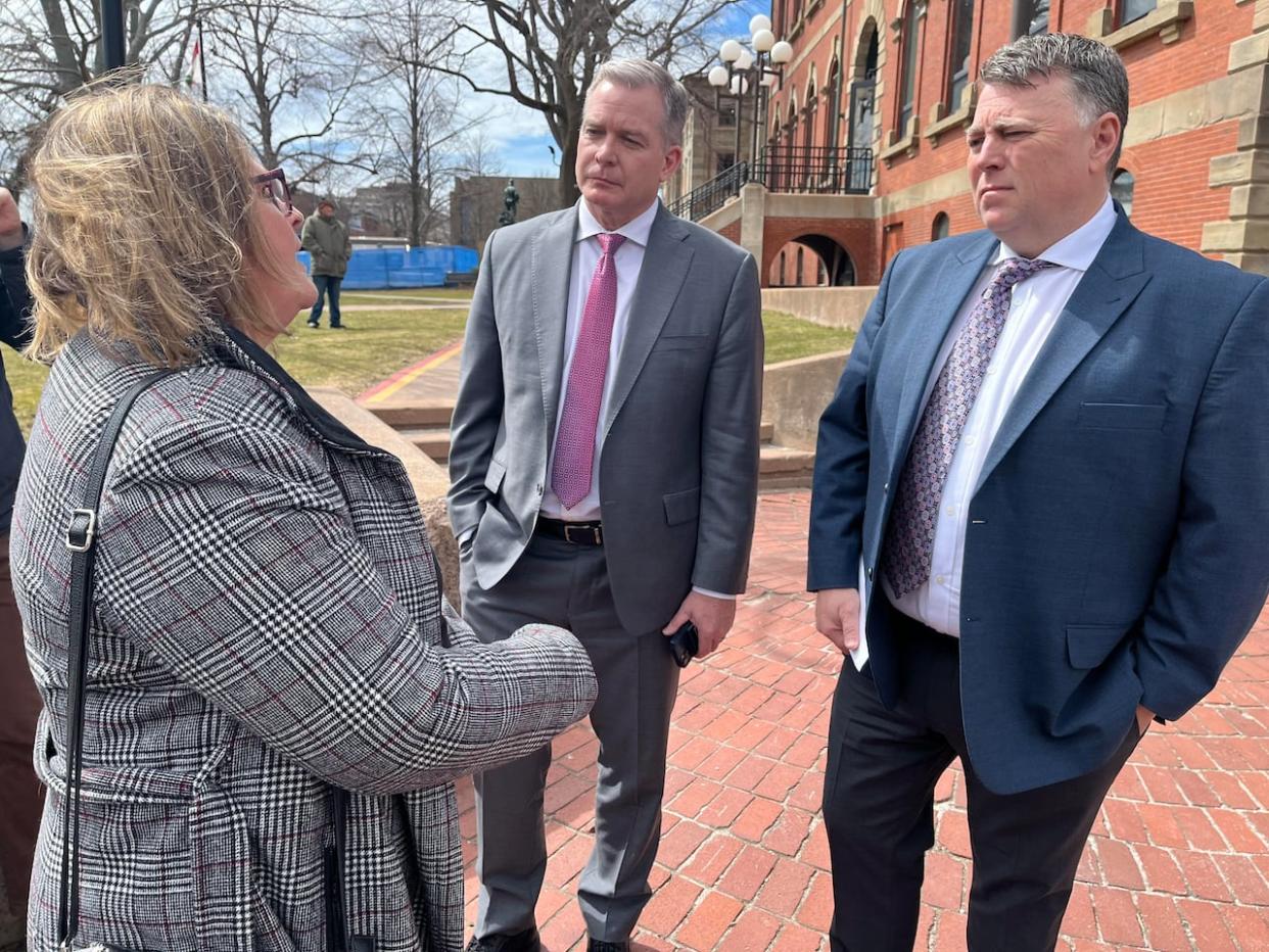 CUPE national servicing representative Lori MacKay, left, speaks with P.E.I. Health Minister Mark McLane, centre, and Premier Dennis King outside the Coles Building in Charlottetown on Thursday. (Wayne Thibodeau/CBC - image credit)